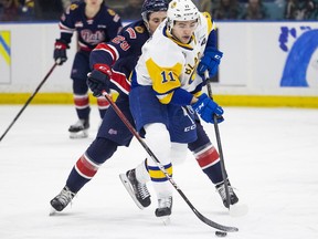 Saskatoon Blades forward Tristen Robins (11) battles for the puck with Regina Pats forward Logan Nijhoff (29) during first period WHL action in Saskatoon on Friday, March 25, 2022.