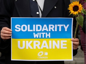 A person carries a banner and a sunflower during a protest in support of Ukraine and against the war, amid Russia's invasion of Ukraine, in Brussels, Belgium March 1, 2022. REUTERS/Yves Herman