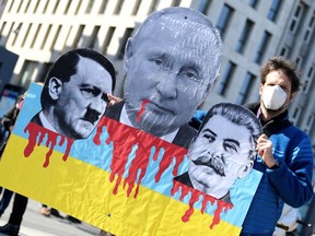 A protester holds a sign with pictures of Russian President Vladimir Putin, Adolf Hitler and Joseph Stalin, during an anti-war demonstration, amid Russia's invasion of Ukraine, in Hamburg, Germany, March 20, 2022. REUTERS/Fabian Bimmer