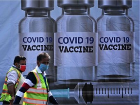 Members of ground staff walk past a container stacked at the Cargo Terminal 2 of the Indira Gandhi International Airport, which will be used as a Covid-19 coronavirus vaccines handling and distribution centre in New Delhi on December 22, 2020. (Photo by Sajjad HUSSAIN / AFP)
