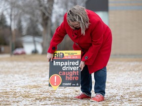 Bonnie Stevenson puts up an "impaired driver caught here" sign for the launch of MADD's mobile sign awareness campaign. Photo taken in Saskatoon, Sask. on Friday, April 1, 2022.