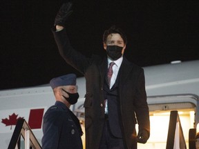 Canadian Prime Minister Justin Trudeau waves as he disembarks a government plane upon his arrival in the United Kingdom, Sunday, March 6, 2022 in London.