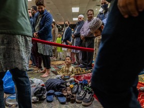 A young boy sits by a pile of shoes as members of the Muslim community gather at Prairieland Park to attend prayers and celebrate Eid-ul-Fitr on May 2, 2022.