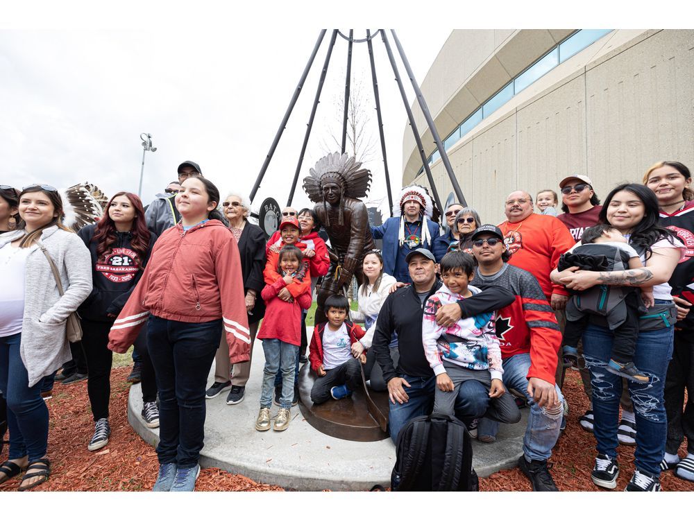 Fred Sasakamoose's family stands for a photo with his bronze statue during the unveiling at SaskTel Centre on Wednesday.