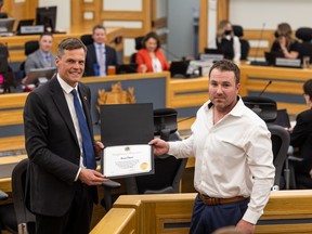 Mayor Charlie Clark, left, presents Brian Gibson with a Certificate of Recognition. City council recognized Gibson, an employee of the City of Saskatoon sign shop who rescued a man in distress in the South Saskatchewan River. Gibson was working out near the river late last month when he spotted the man struggling in the water and leapt in to save him.