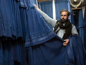An Afghan vendor displays a burqa at his shop at Mandawi market in Kabul on May 8, 2022. The Taliban on May 7 ordered Afghan women to cover fully in public, ideally with the traditional burqa.