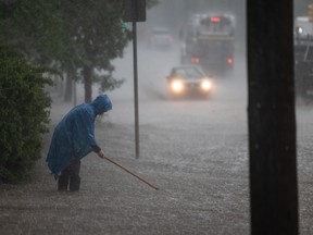 A person attempts to clear a drain along Clarence Avenue as heavy rains caused flooding around Saskatoon, SK on Monday, June 20, 2022.