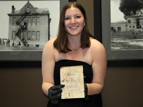 Kerrobert museum's summer curator Breena Hebron shows off a 102-year-old artifact from the town's recently-rediscovered time capsule.