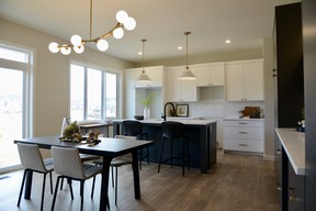 Twin pantry cabinets flank a built-in desk, a large quartz-topped island, and beautiful tile back splash make this kitchen modern and functional for any busy family.