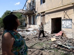 People walk past their partially destroyed building following a Russian airstrike in the town of Toretske, in the Donetsk region, Sunday, July 17, 2022, amid the Russian military invasion of Ukraine.