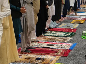 Worshippers stand as prayer begins and their colourful prayer mats are revealed at Prairieland Park in Saskatoon for Eid al-Adha on July 9, 2022.