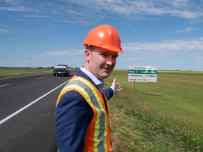 Minister Jeremy Cockrill motions to the passing lane investment sign beside the passing lane on Highway 7 just outside of Kindersley on Friday, July 22, 2022.