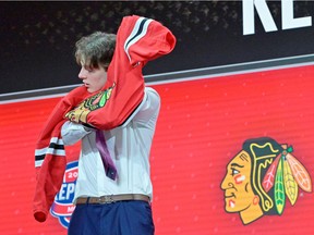Saskatoon's Kevin Korchinski pulls on his Blackhawks sweater after being selected seventh overall in this week's NHL draft. (Eric Bolte USA TODAY Sports)