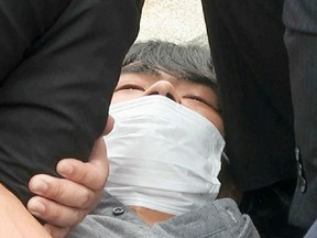 This screen grab shows the suspect, identified as Tetsuya Yamagami, believed to have shot former Japanese Prime Minister Shinzo Abe, being held by police officers in Nara, western Japan, July 8.