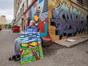 Paul Sisetski, un résident du Centre communautaire de Sherbrooke, pose avec son tableau The Long Road Home, à l'extérieur du mur d'art du bâtiment Drinkle, le 2 août, où son œuvre sera ajoutée cette semaine.
