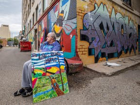Paul Sisetski, a Sherbrooke Community Centre resident, poses with his painting, The Long Road Home, outside the Drinkle building art wall on Aug. 2, where his artwork is being added this week.