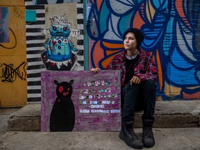 Charli sits with their painting Mothman Says outside the Drinkle building, where their artwork is being added this week. Photo taken in Saskatoon, SK on Tuesday, August 2, 2022.