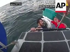 A father and son who were desperately clinging to a cooler at the outermost edge of Boston Harbor after their lobster boat sank are pictured being rescued by Boston police in this screengrab of a body camera video.