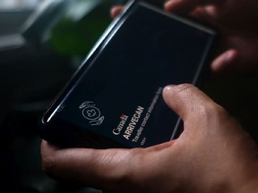 A person holds a smartphone set to the opening screen of the ArriveCan app in a photo illustration made in Toronto on June 29.