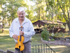 John Arcand stands with one of his fiddles in front of his home, which was also the home to the John Arcand Fiddle Festival for nearly 25 years.