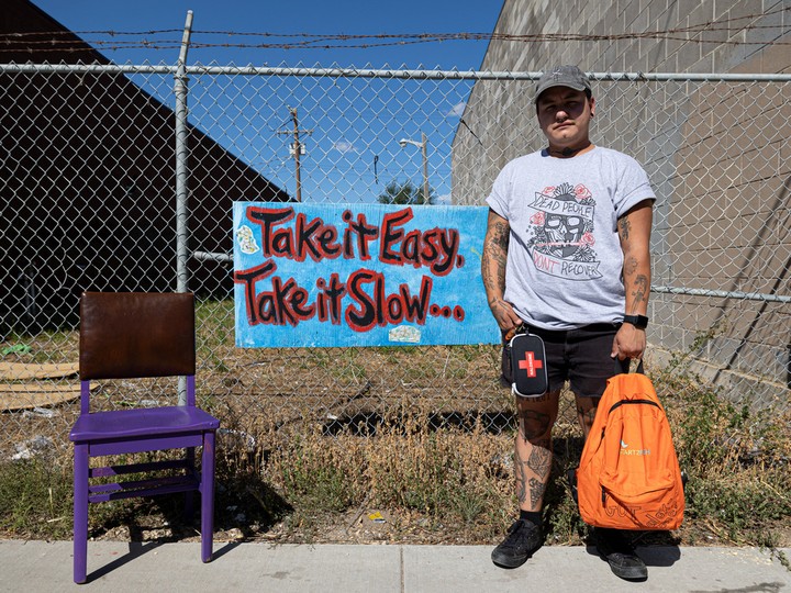  Tuk Gordon, a harm reduction advocate in Saskatoon who is helping organize overdose awareness day in the city, stands with an empty purple chair, wearing a T-shirt he made to spread awareness about the crisis in Saskatchewan.