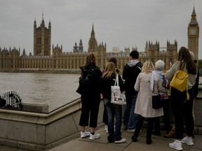 Tourists stand outside of Westminster Place in London, Tuesday, Sept. 13, 2022. Queen Elizabeth II, Britain's longest reigning monarch, will lay in state at Westminster Palace from Wednesday.