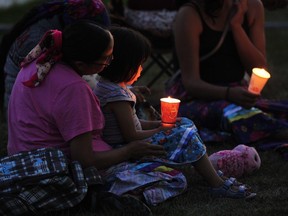 People sit together at at a vigil held for the victims of a mass killing in and near James Smith Cree Nation, which was held at the First Nations University of Canada in Regina, Saskatchewan on September 7, 2022.