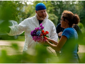 Ruby Works speaks with a forensic investigator before bringing flowers to the home of a victim who has been identified by residents as Wes Petterson in Weldon, Sask., on Monday, Sept. 5, 2022. Works said that the 77-years-old victim was like an uncle to her.