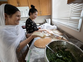 Rejna Ahmadi helps her mom Zubida Yousfi prepare a comforting meal of bulani in the kitchen of their new home in Saskatoon on Jan. 17, 2022.