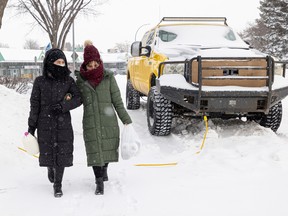 Rejna Ahmadi (left) and Shakiba Ahmadi hold onto each other as they carefully walk home in the freezing cold with their groceries from the nearby convenience store in Saskatoon on Jan. 7, 2022.