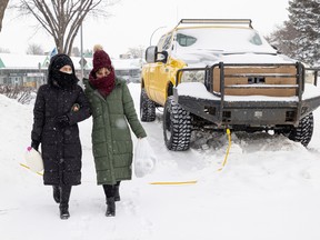 Rejna Ahmadi (left) and Shakiba Ahmadi hold onto each other as they carefully walk home in the freezing cold with their groceries from the nearby convenience store in Saskatoon.