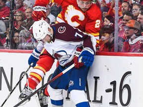 Brett Ritchie of the Calgary Flames chases the puck against Devon Toews of the Colorado Avalanche during an NHL game at Scotiabank Saddledome on October 13, 2022 in Calgary, Alberta, Canada.