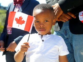 Brian Egbe waves a flag during a public citizenship ceremony at the Calgary Stampede on July 11, 2022.