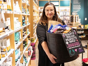 Nicole White, founder of Moon Time Sisters and Saskatchewan chapter lead, holds up a basket of donated period products at the Body Shop in Centre Mall, Oct. 7, 2022. They have a donation drive through October for menstrual products to send to northern communities.