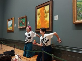 A handout picture from the Just Stop Oil climate campaign group shows activists with their hands glued to the wall under Vincent van Gogh's "Sunflowers" after throwing tomato soup on the painting at the National Gallery in central London on October 14, 2022.