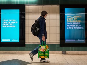 People walk past advertising enticing people to move to Alberta, in the TTC subway at Yonge and Bloor, Thursday September 29, 2022.