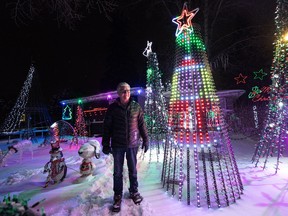 Scott Lambie stands next to his favourite part of his elaborate Christmas lights display — a programmed Mariah Carey Santa Claus that dances along to her famous "All I want for Christmas" song in Saskatoon, Nov. 29, 2022. This will be the 15th and last year for the "Clinkskill House" animated Christmas lights display.