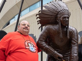 Neil Sasakamoose stands alongside the statue of his dad Fred Sasakamoose during the statue's unveiling at SaskTel Centre. Photo taken in Saskatoon, Sask. on Wednesday May 18, 2022.