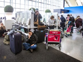 Passenger dealing with delays and cancellations wait in line for phone to contact the airlines at Terminal 1 departures level at Toronto Pearson International Airport on Friday, Dec. 23, 2022.