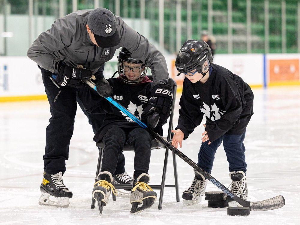 Huskies head coach Brandin Coté helps Cohen Stone and Isaiah Gauthier try out the Para sport of blind hockey Tuesday at Merlis Belsher Place.