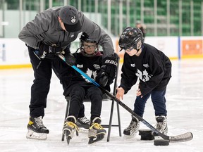 Huskies head coach Brandin Coté helps Cohen Stone and Isaiah Gauthier try out the Para sport of blind hockey Tuesday at Merlis Belsher Place.