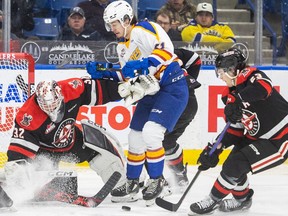 Saskatoon Blades forward Jake Chiasson (61) tries to deflect a shot past Moose Jaw Warriors goalie Connor Ungar (32) during WHL action in Saskatoon on Wednesday, January 18, 2023.