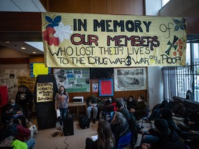 Laura Shaver, back left, speaks at a gathering to remember those who died from a suspected illicit drug overdose, in Vancouver, on Wednesday, February 9, 2022. British Columbia is introducing a policy of decriminalization on Tuesday as part of what it says is an overall plan in its fight against overdose deaths from illicit drugs.