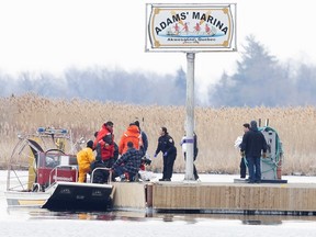 Police and firemen carry a bag off their search boat from the marshland in Akwesasne, Quebec March 31, 2023.