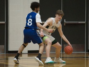 Holy Cross's Owen Shepherd-Hills (right) protects the ball from Walter Murray's Abde Tagiuri during the 2023 5A boys provincial high school basketball final at Hoopla in Prince Albert on March 25, 2023.