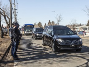 Police salute during a procession to a funeral home for Const. Travis Jordan and Const. Brett Ryan in Edmonton on Tuesday, March 21, 2023. A regimental funeral is set to be held Monday for the two officers, who were shot and killed while responding to a family dispute.