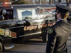 Fire fighters salute as the hearse and honour guard pass by at the regimental funeral service for Calgary Police Service Sgt. Andrew Harnett in Calgary, Alta., Saturday, Jan. 9, 2021. A sentencing hearing is scheduled to begin today for a youth found guilty of manslaughter in the hit-and-run death of a Calgary police officer.