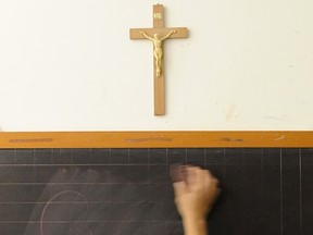 A teacher cleans a blackboard under a crucifix in a classroom of a school in this 2010 photo.