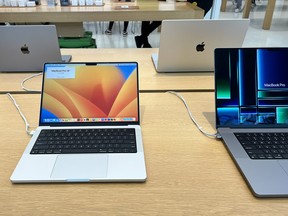 Four laptop computers sit on a table in a brightly-lit room.
