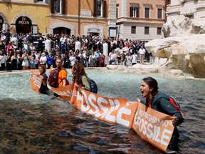 Climate activists hold a banner after pouring vegetable charcoal in the Trevi Fountain water, during a demonstration against fossil fuels, in Rome, Italy May 21, 2023 in this image obtained from social media.
